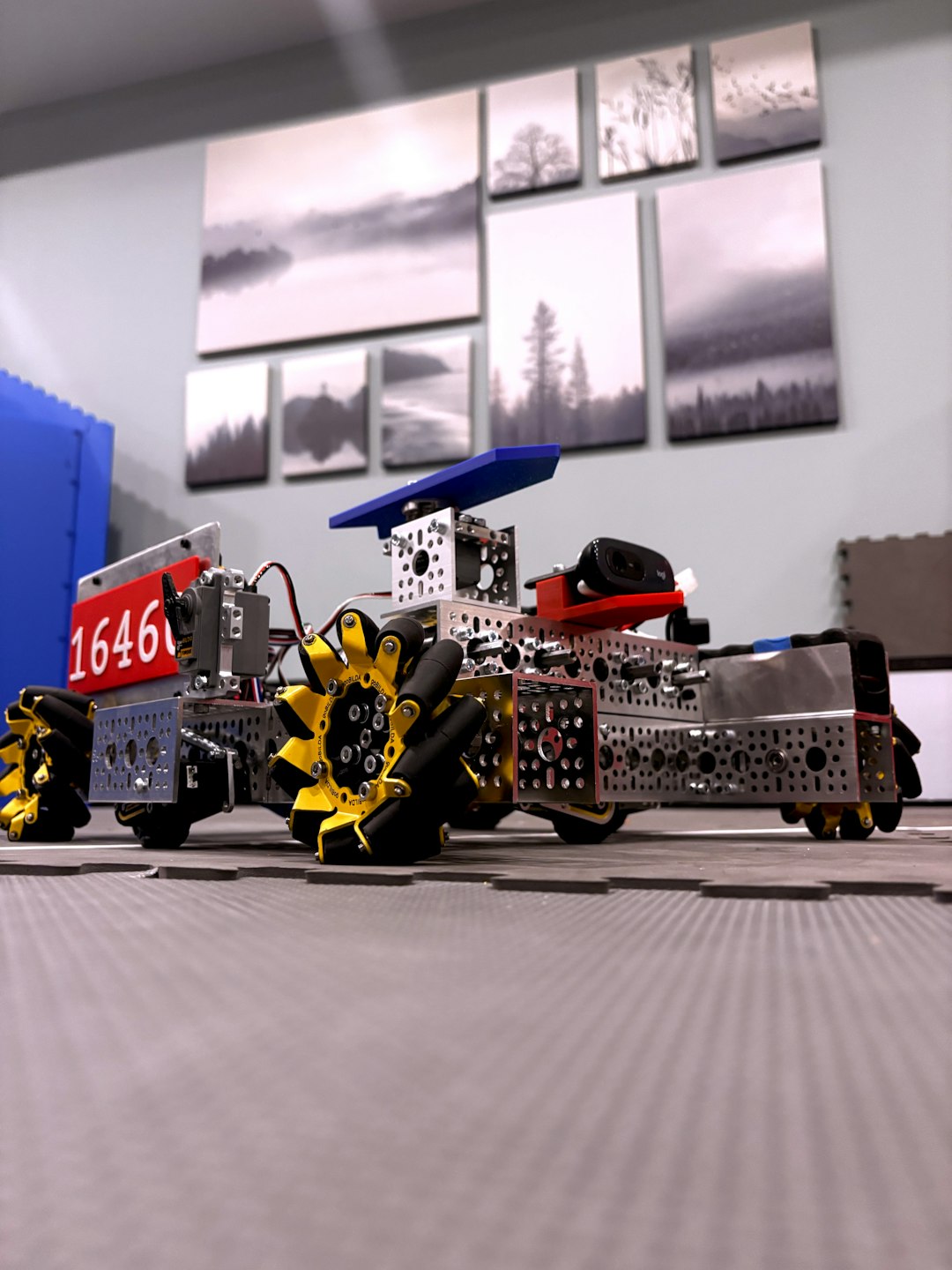 a-complex-robot-with-yellow-wheels-on-a-mat-nme3tnsoebo